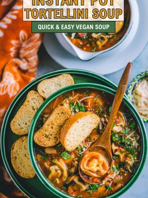 Vegan tortellini soup with beans and herbs served hot in a ceramic bowl and text at the top and bottom.
