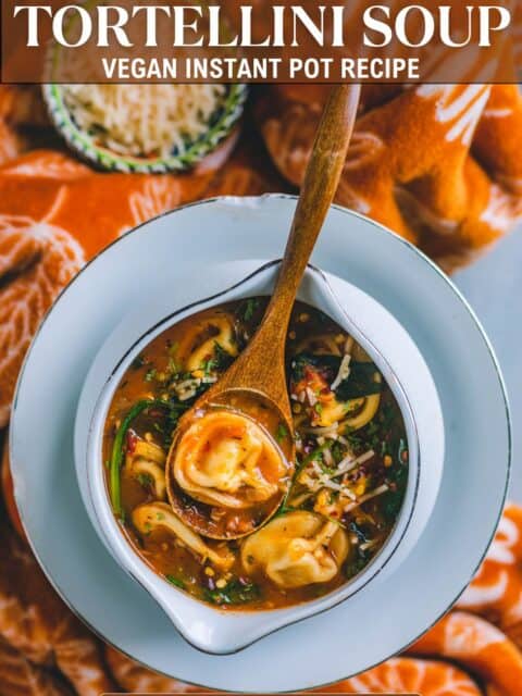 Wholesome vegan tortellini soup garnished with fresh cilantro and chili flakes and text at the top and bottom.