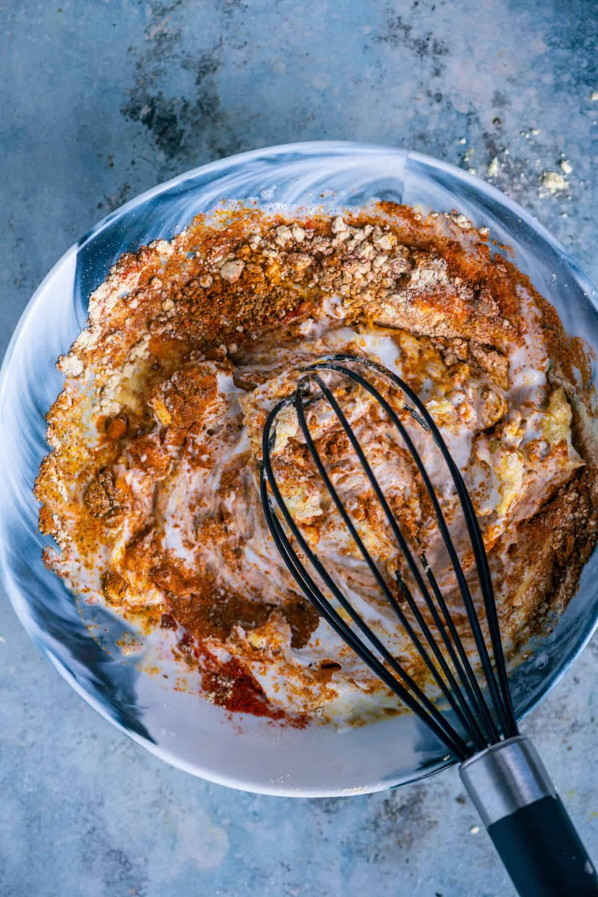 Whisking the yogurt and spice mixture until smooth, creamy, and lump-free.
