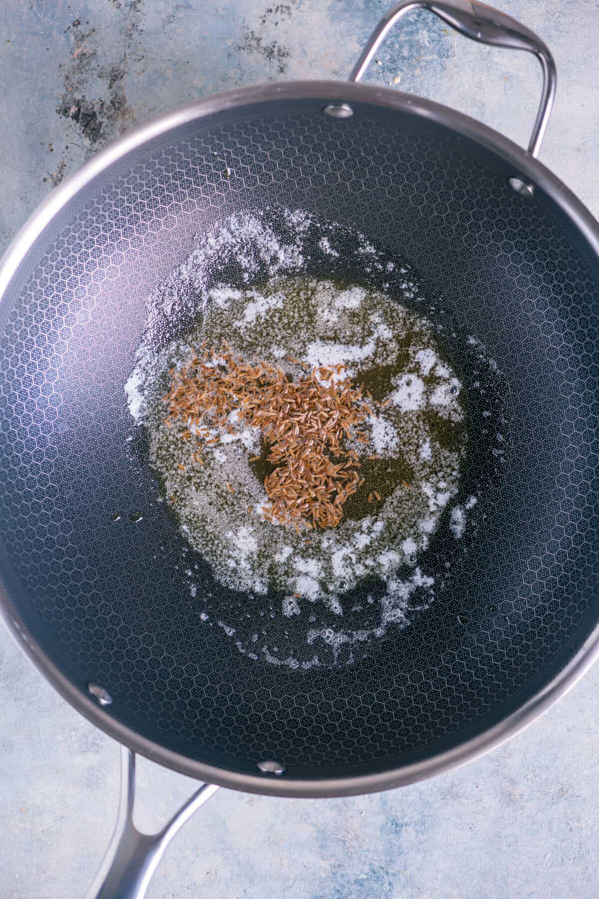 Heating butter and oil in a pan and tempering cumin seeds until aromatic.