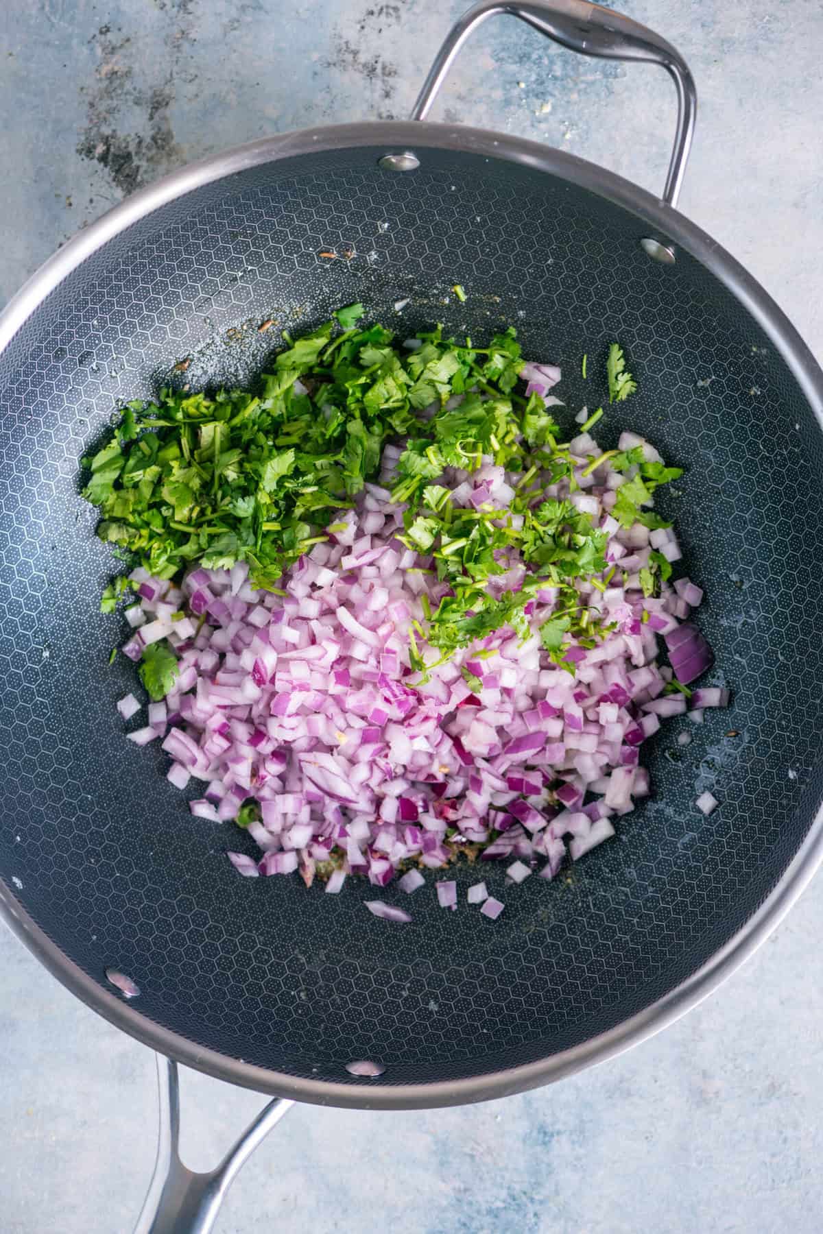 Cooking chopped onions and finely chopped cilantro stalks until onions turn translucent.