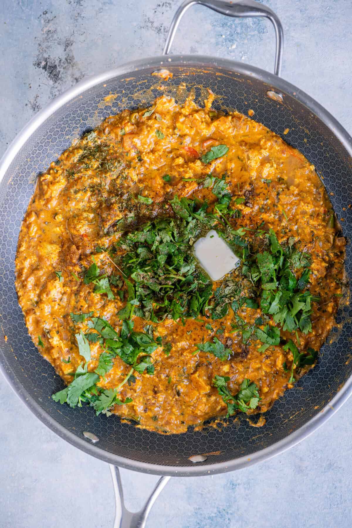 Finishing the Paneer Bhurji with butter, fresh cilantro, a squeeze of lemon juice, kasuri methi, and a sprinkle of chaat masala.