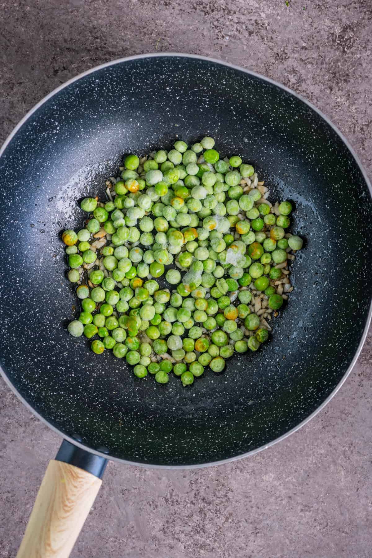 Green peas sautéed in a pan for vegan breadcrumbs pasta.