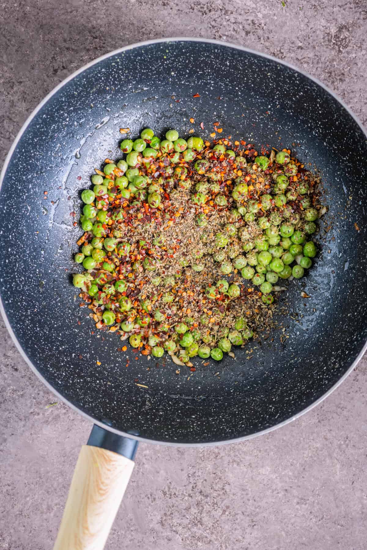 Adding seasoning - herbs and red pepper flakes - to breadcrumbs pasta.