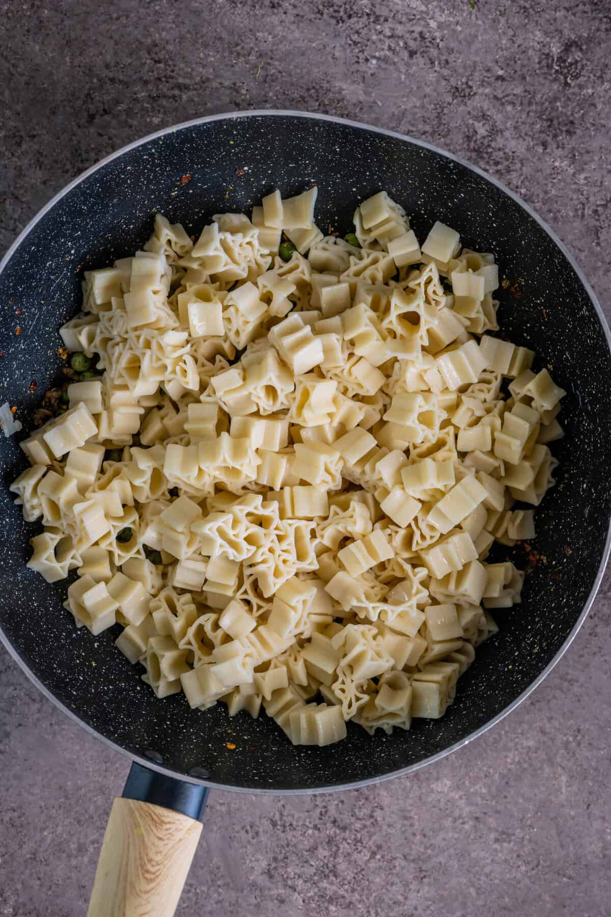 Tossing cooked pasta in a pan with garlic and herbs for pangrattato pasta.