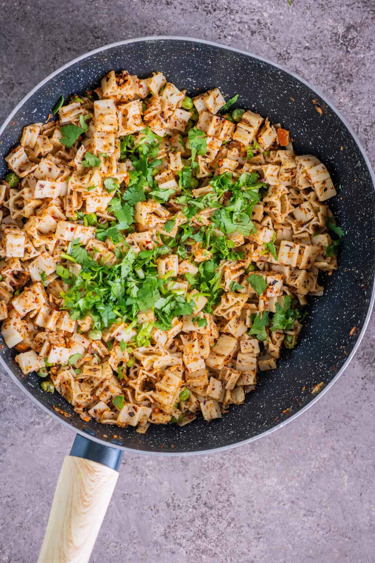 Mixing fresh cilantro into pasta with breadcrumbs for flavor and color.