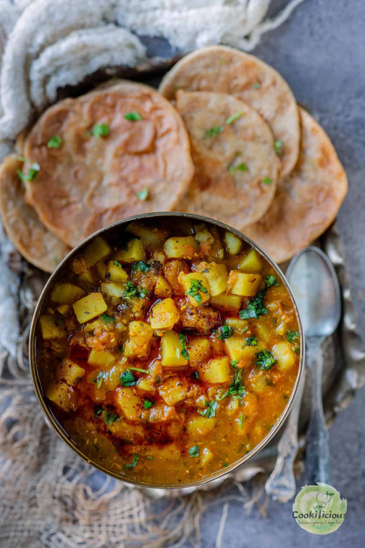 Traditional aloo poori platter with potato curry, crispy puris, and fresh cilantro garnish—popular Indian vegan breakfast.