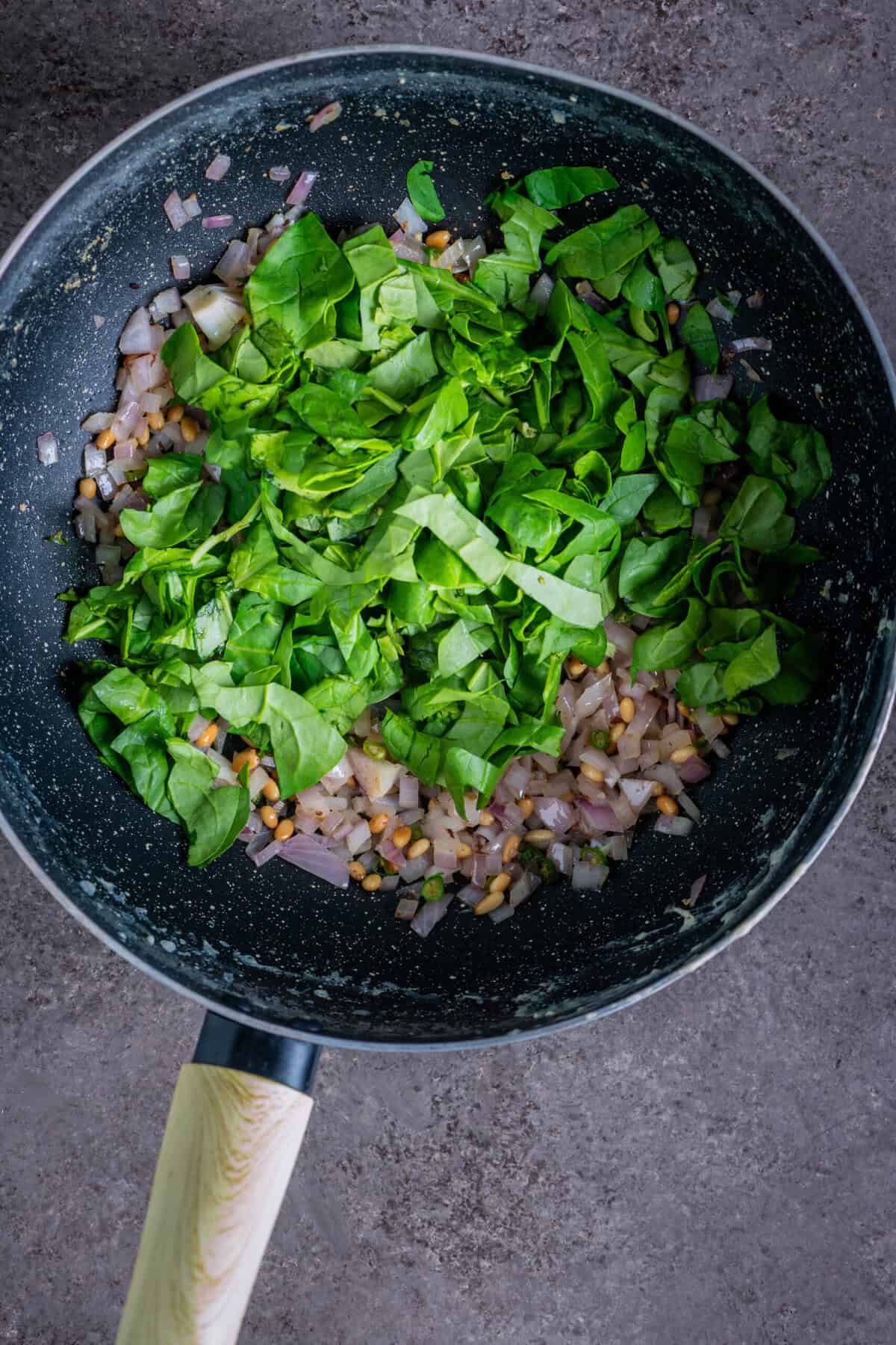 Fresh spinach wilting as it cooks down into the onion mixture.