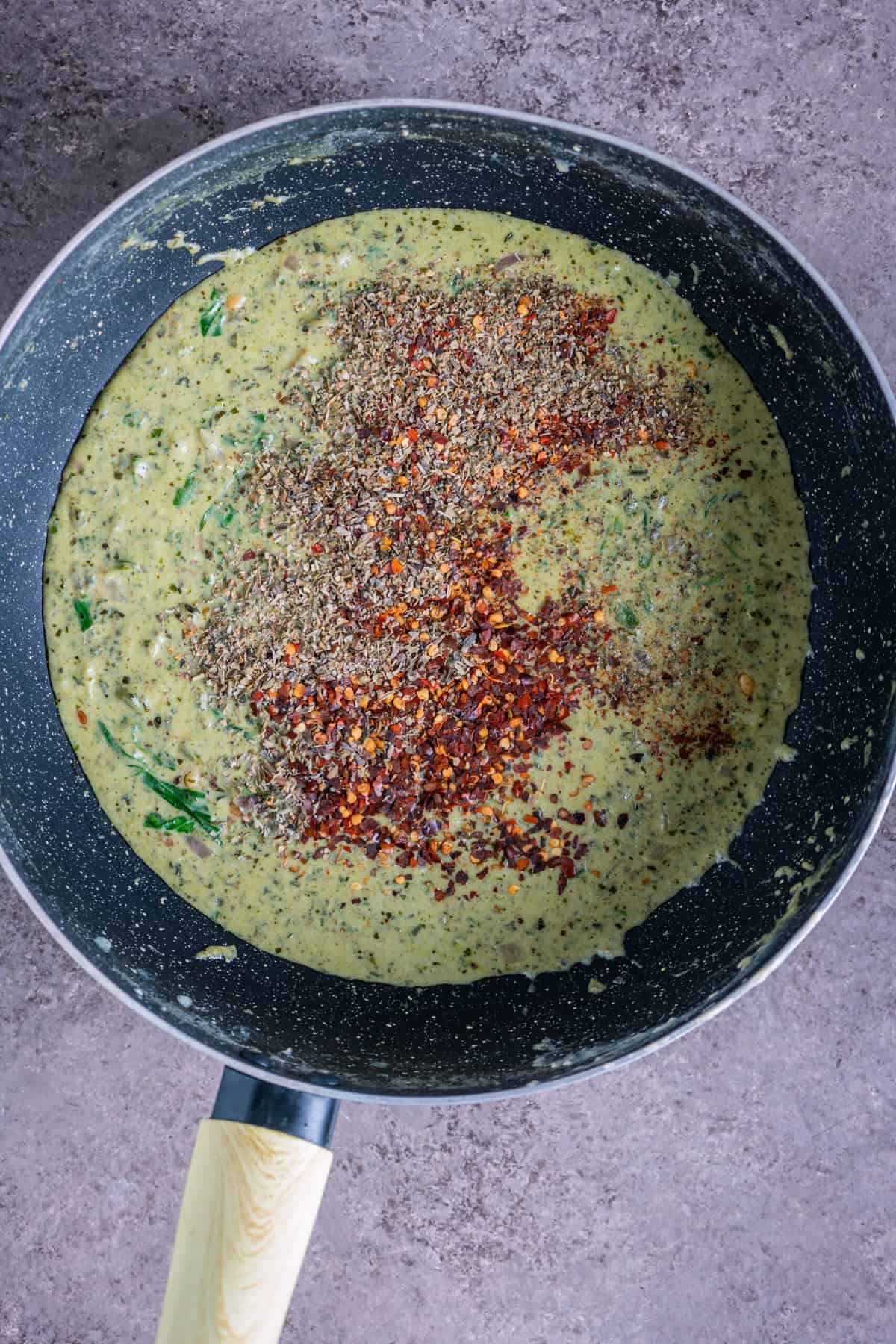Seasonings-Italian seasoning, red pepper flakes, and salt-being sprinkled into the sauce.