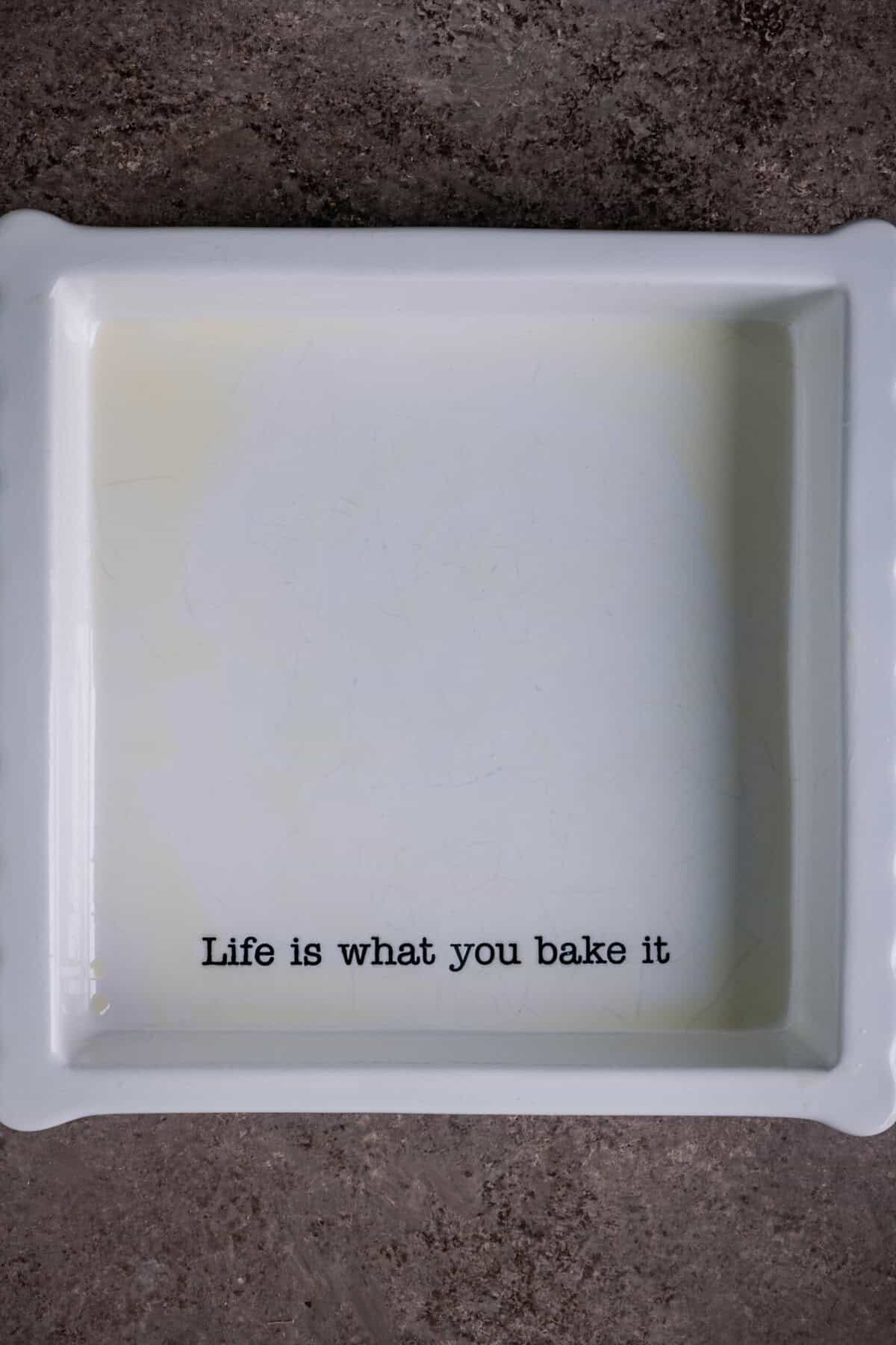 Butter being spread inside a baking dish to grease it.
