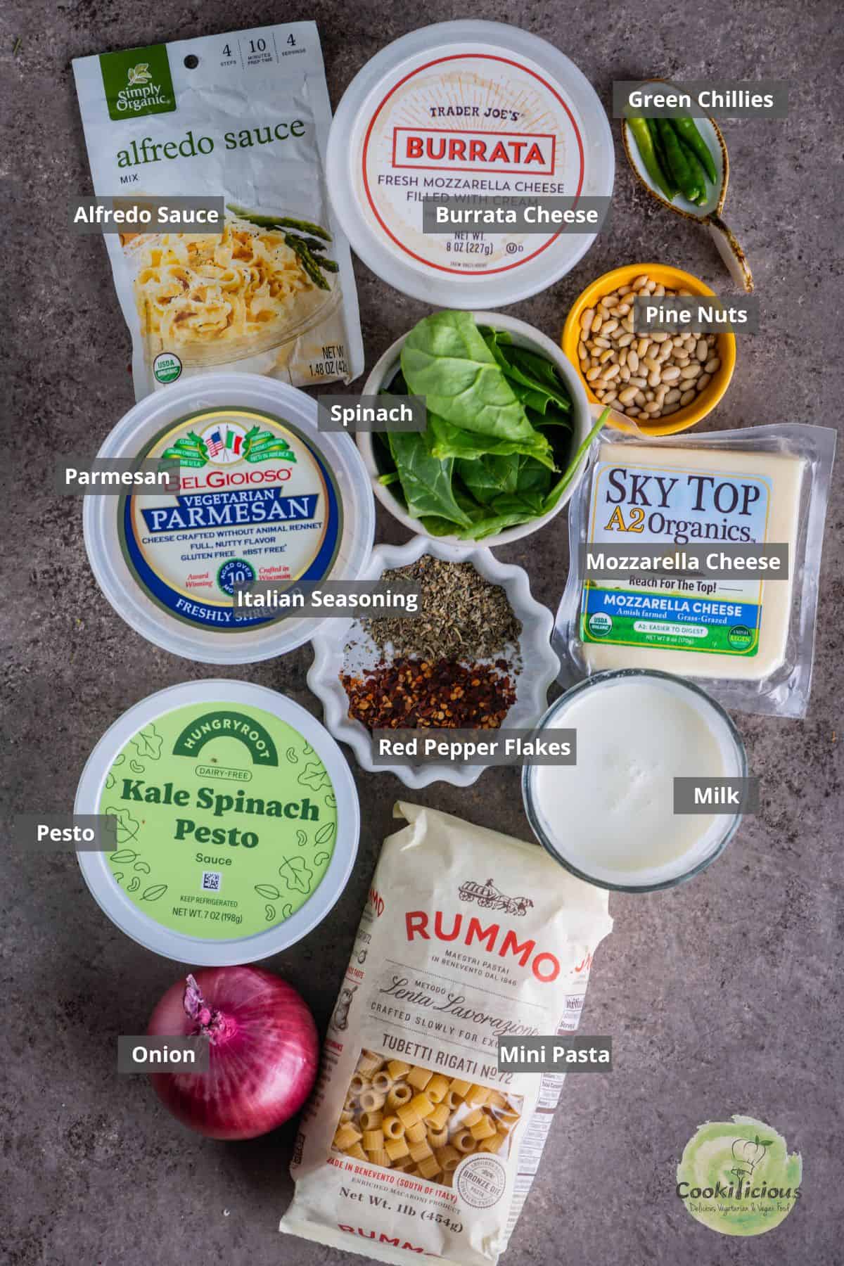 all the ingredients needed to make pesto pasta bake placed on a table with labels on them.