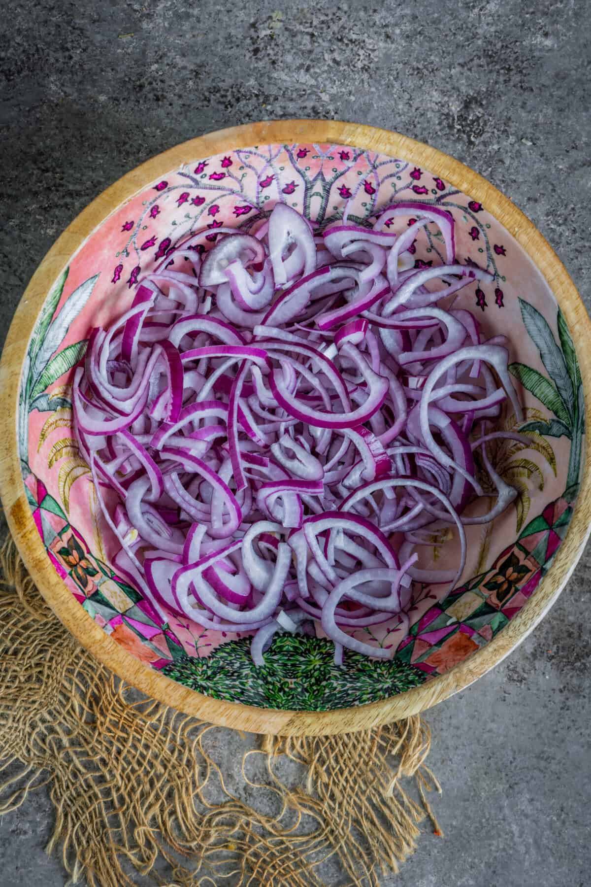Sliced red onions in a bowl, cut into thin wedges for Indian onion salad.