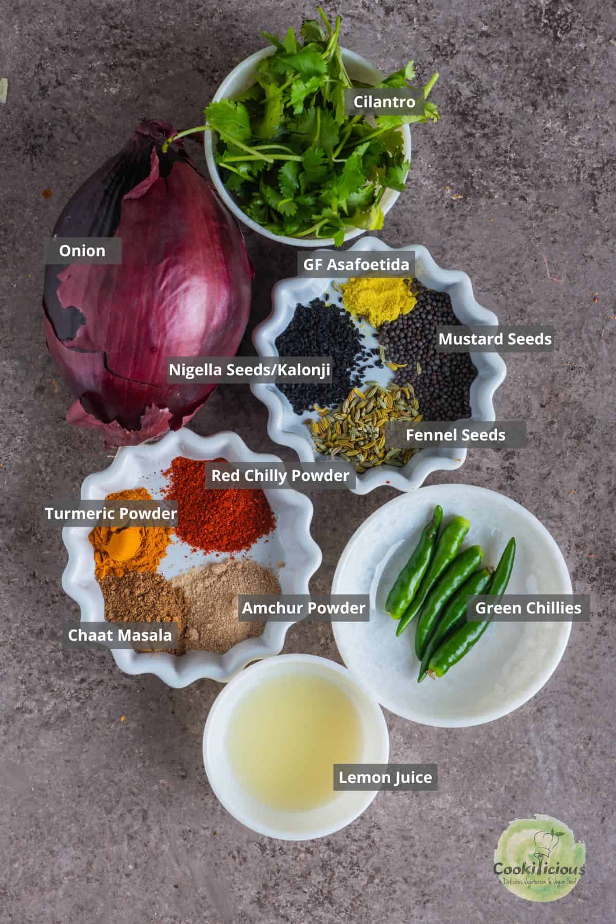 All the ingredients needed to make Indian red onion salad placed on a table with labels on them.