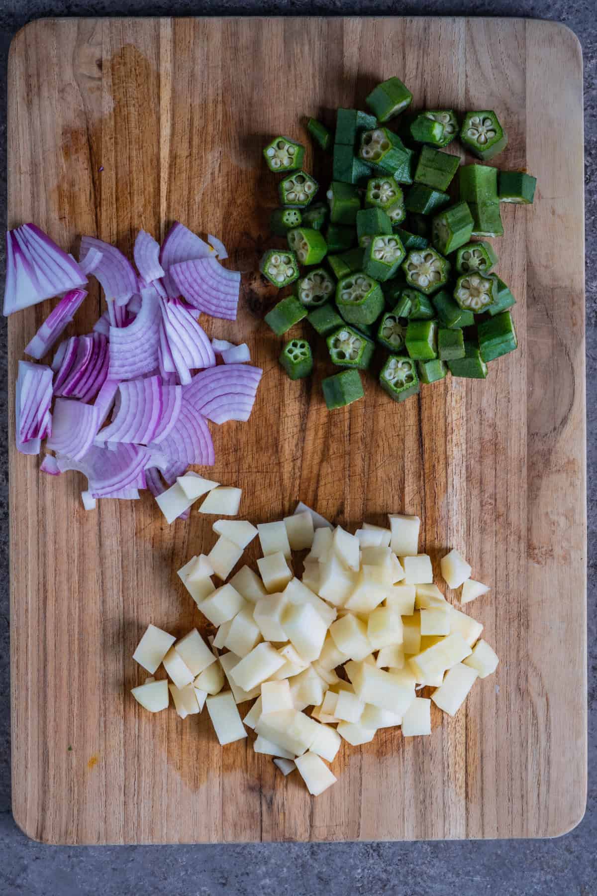 Sliced fresh bhindi (okra), sliced onions, and cubed potatoes, ready for Aloo Bhindi stir-fry.