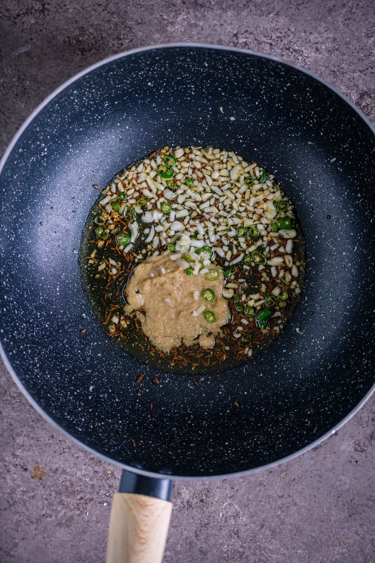 Cumin seeds spluttering in hot oil with minced green chilies, garlic, and ginger paste for Indian Aloo Bhindi base.