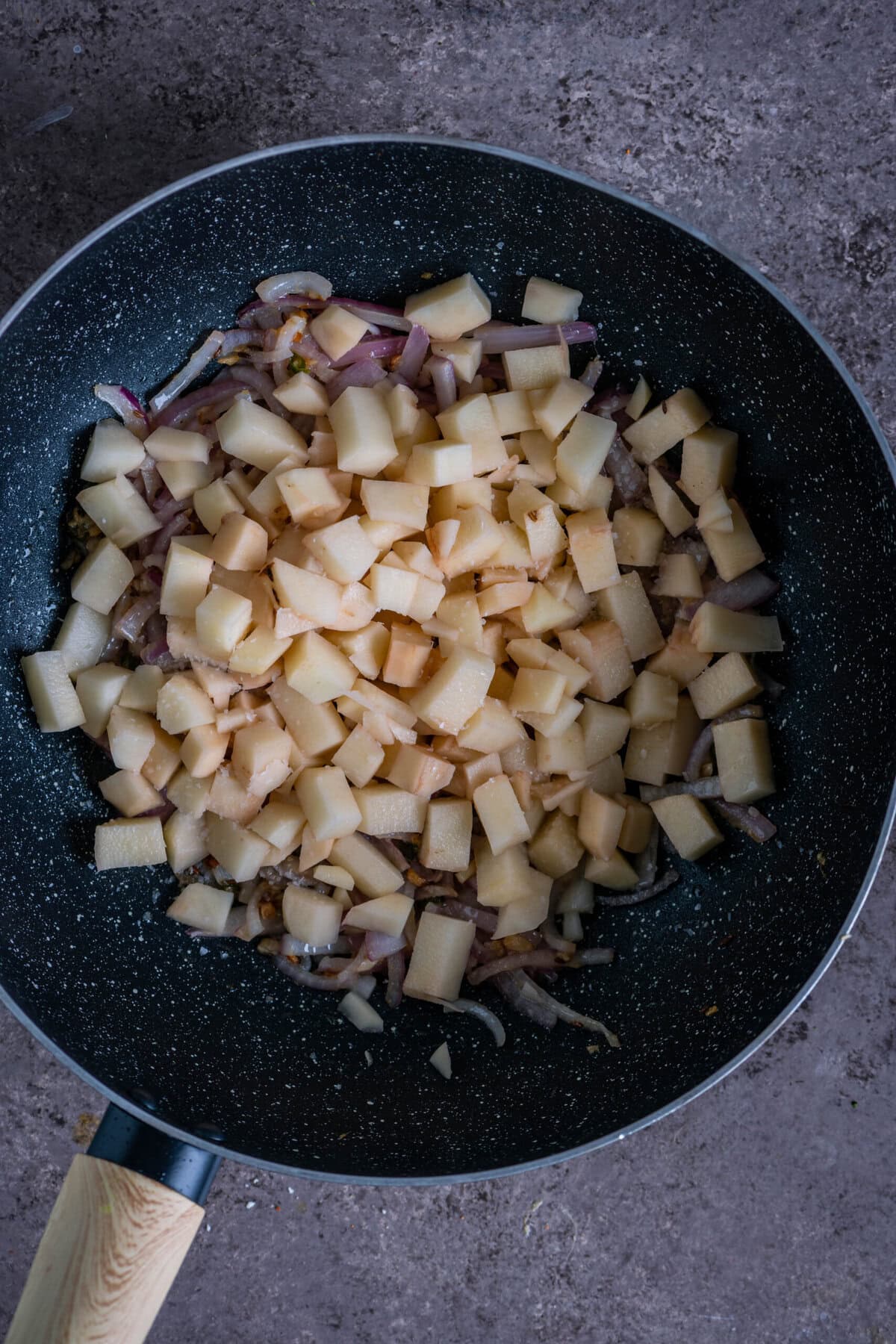 Potato cubes added to the pan, partially cooked and coated with spices for Aloo Bhindi.
