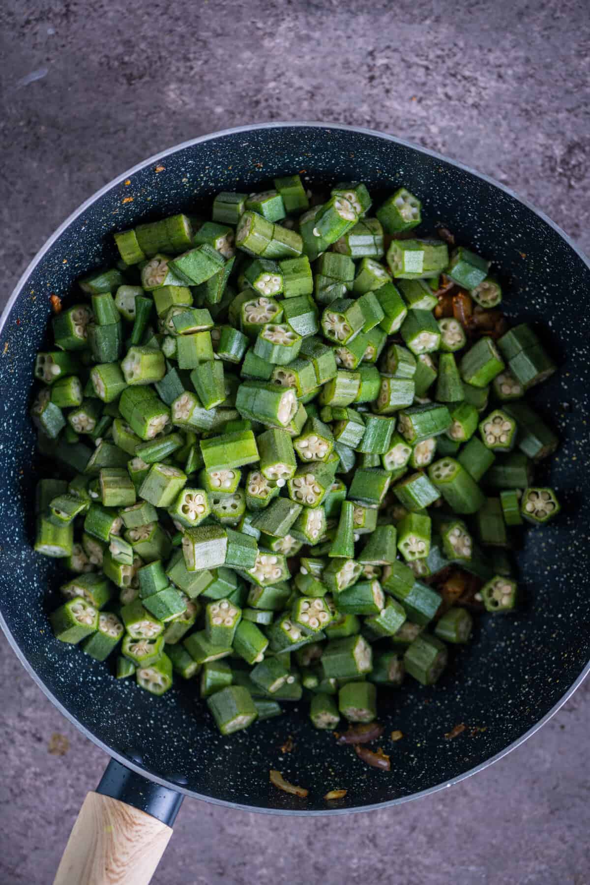 Sliced bhindi gently mixed with spiced potatoes in a pan for restaurant-style Aloo Bhindi.