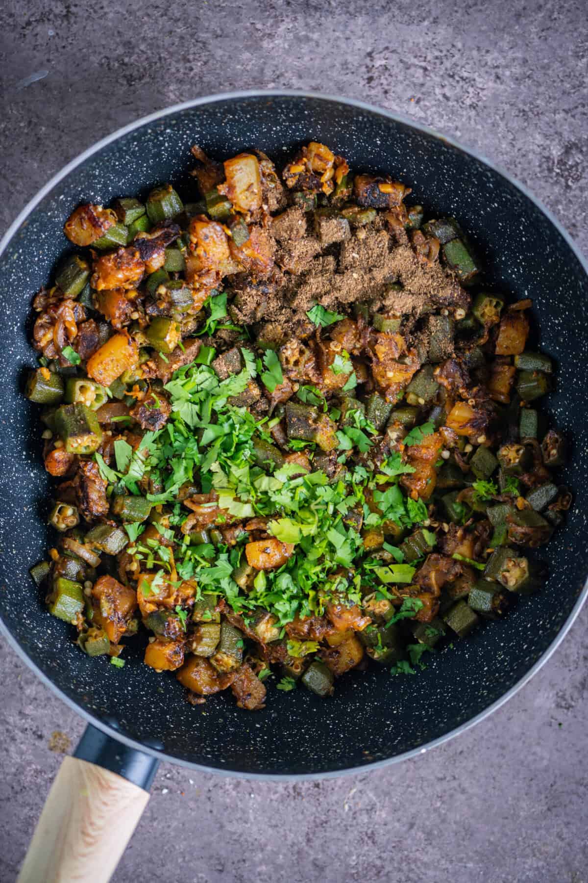 Finished Aloo Bhindi garnished with garam masala, chopped cilantro, and a squeeze of lemon, ready to be served with roti or rice.