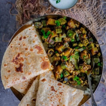 Indian Aloo Bhindi sabzi plated with roti, featuring a vibrant mix of sautéed okra and potatoes.