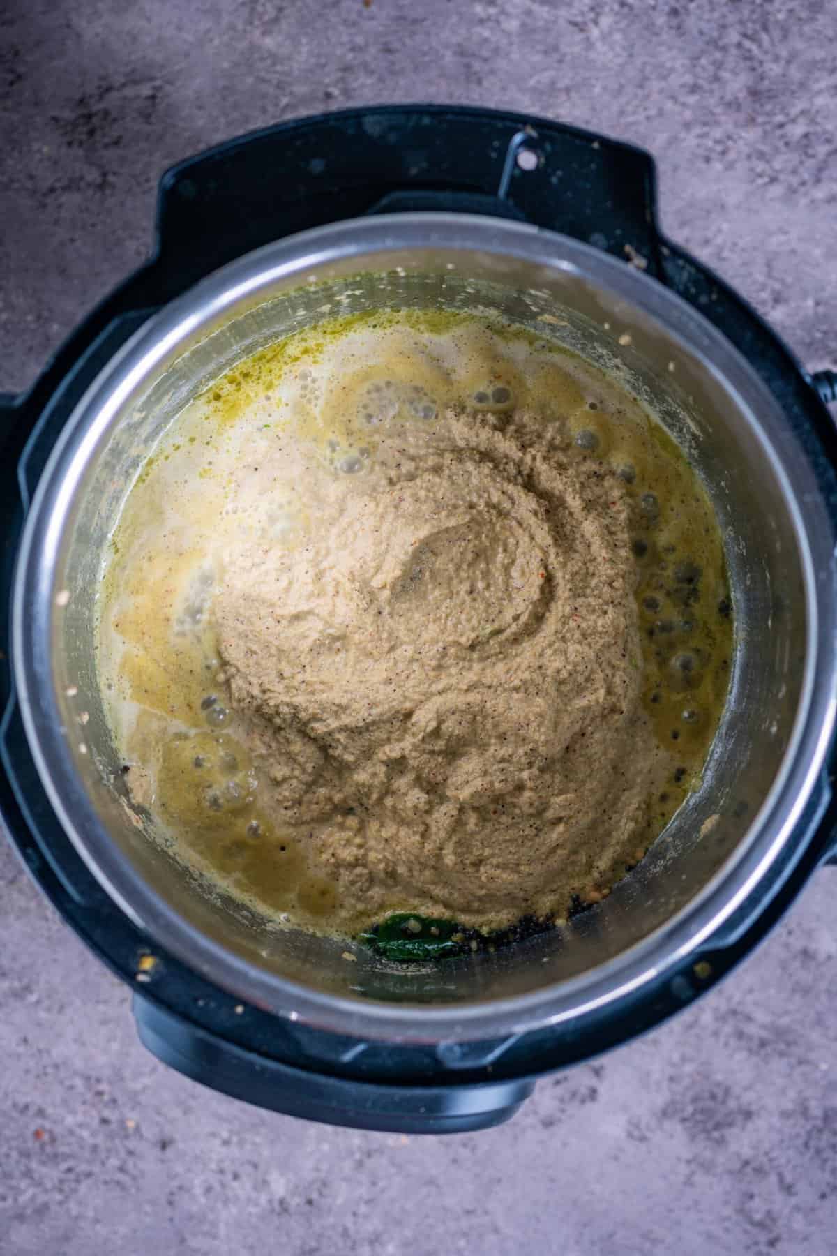 Freshly ground coconut masala being sautéed with little water in the Instant Pot for Poricha Kootu.