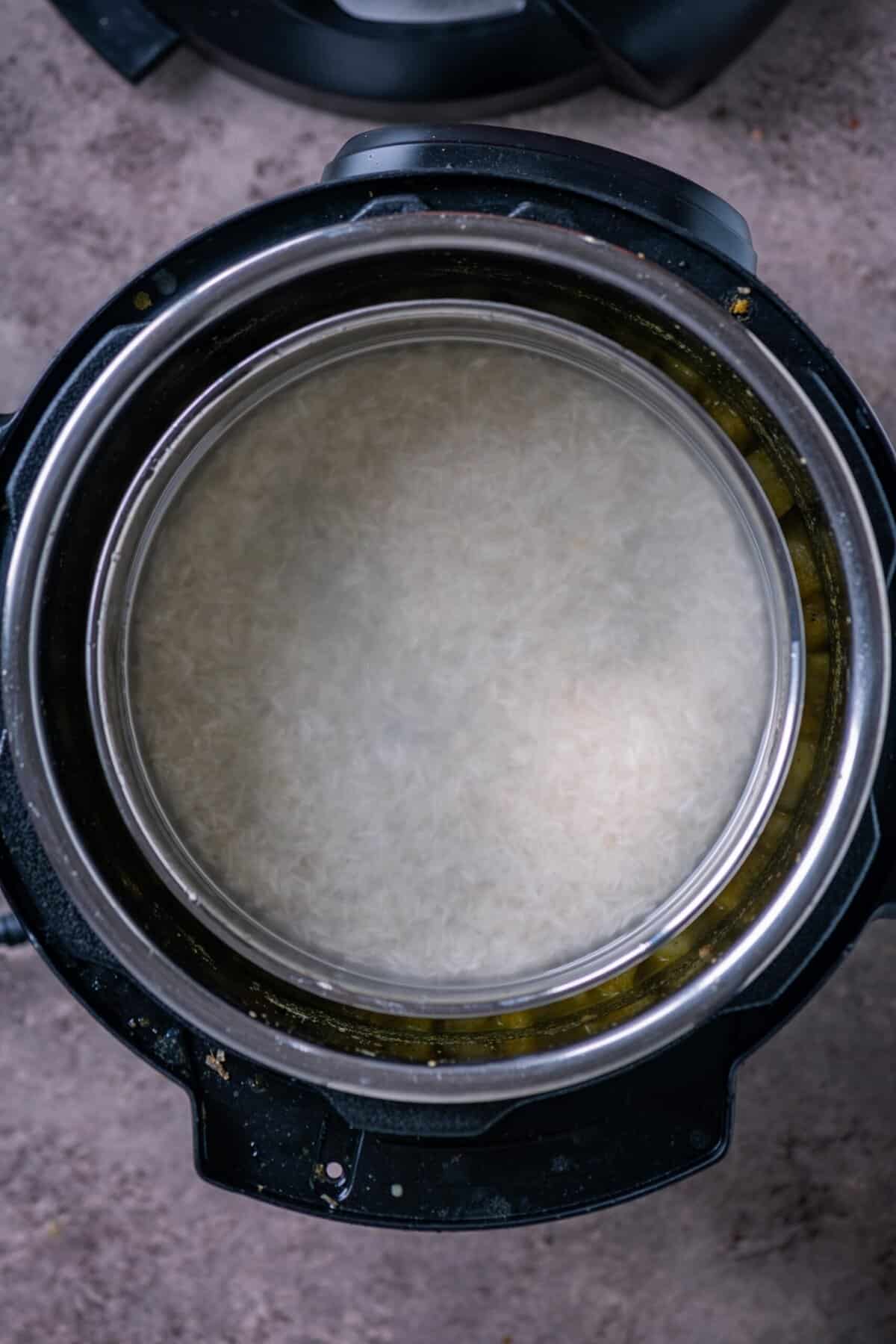 Pot-in-pot rice setup sitting on a trivet above the kootu ingredients inside the Instant Pot.