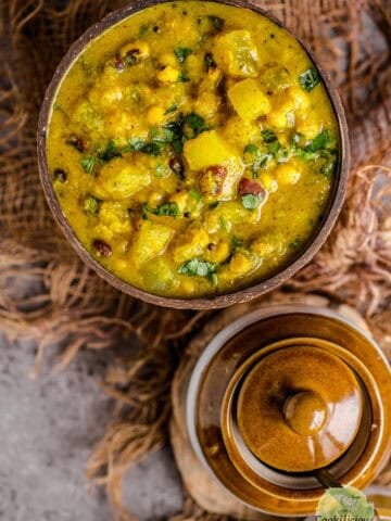 Bowl of creamy Poosanikai Kootu garnished with fresh cilantro, showing tender white pumpkin pieces.
