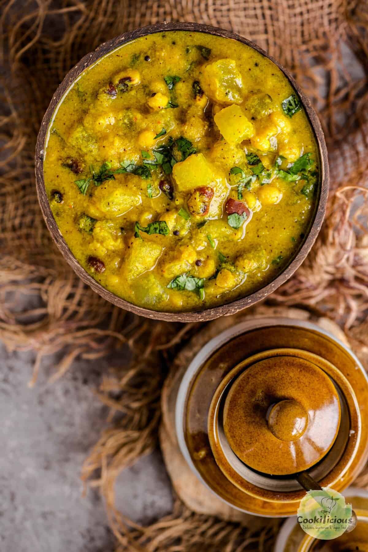 Bowl of creamy Poosanikai Kootu garnished with fresh cilantro, showing tender white pumpkin pieces.