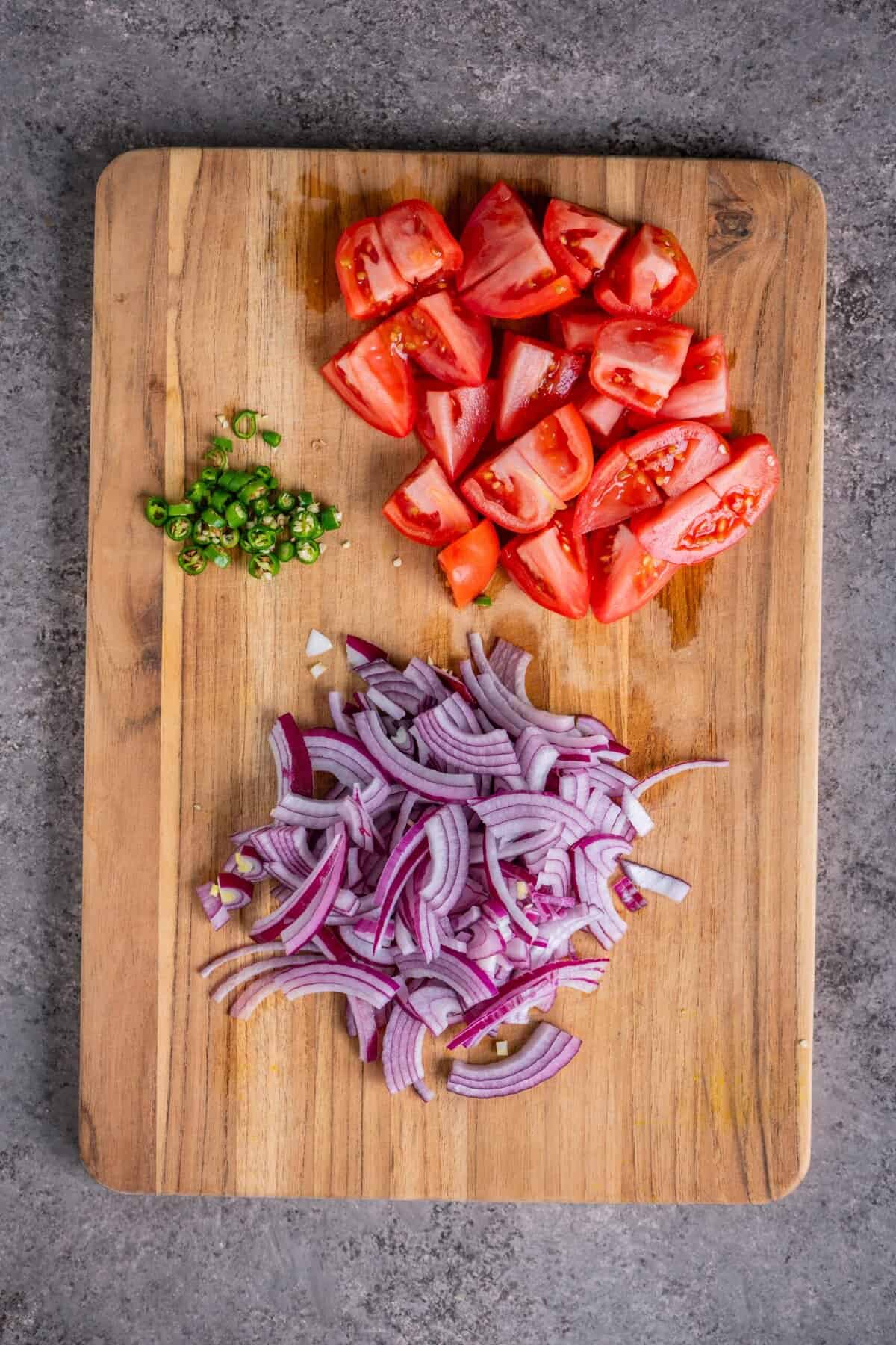 Chopped tomatoes, sliced onions, and green chilies prepared for vegetable upma.