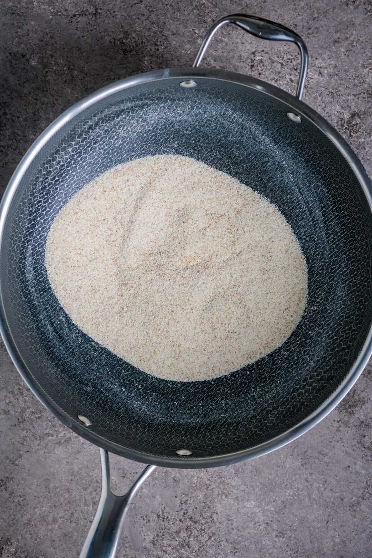 Dry roasting coarse rava in a pan for fluffy tomato upma recipe.