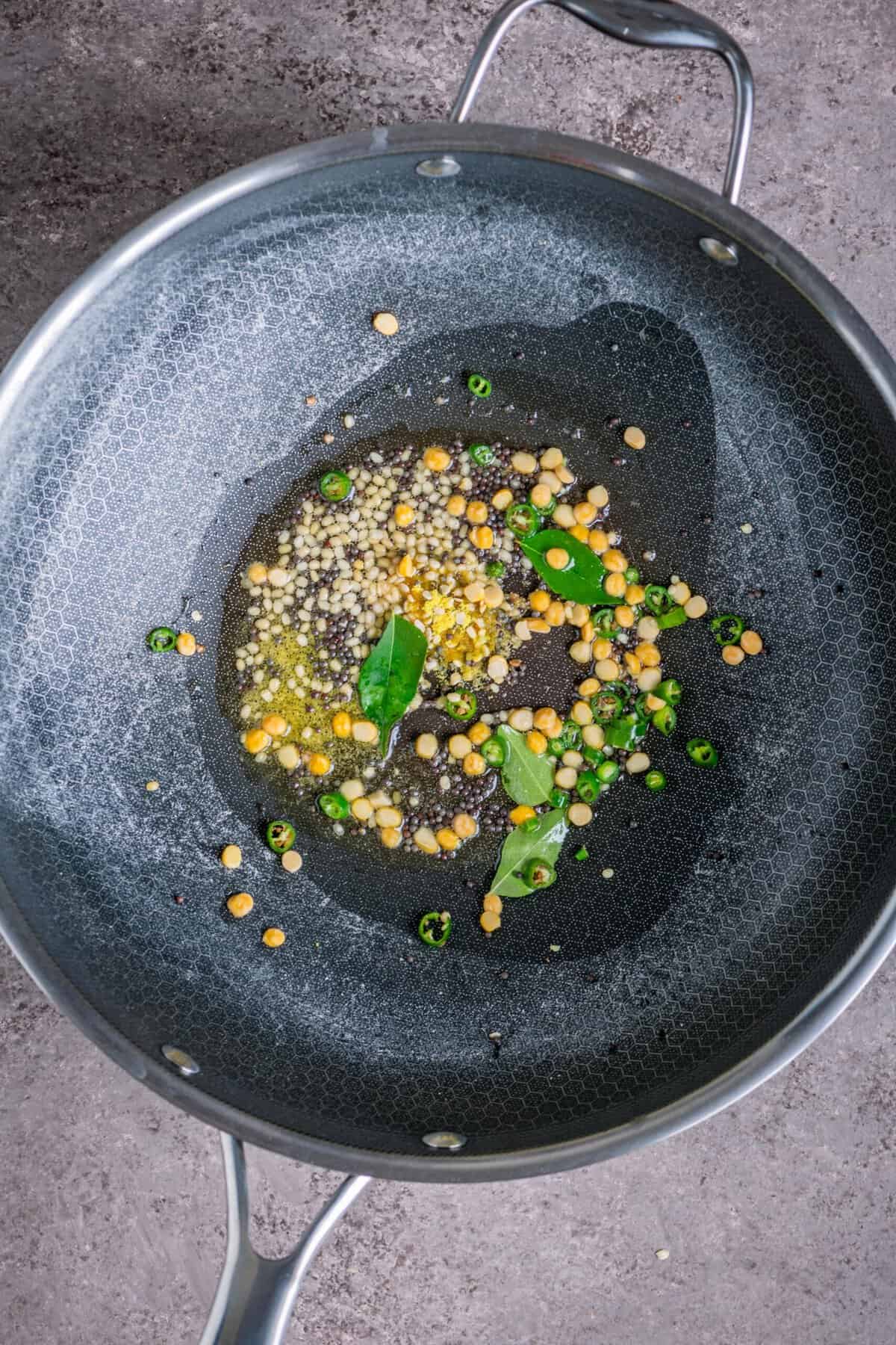 Mustard seeds, lentils, curry leaves tempering in vegan ghee for upma recipe.