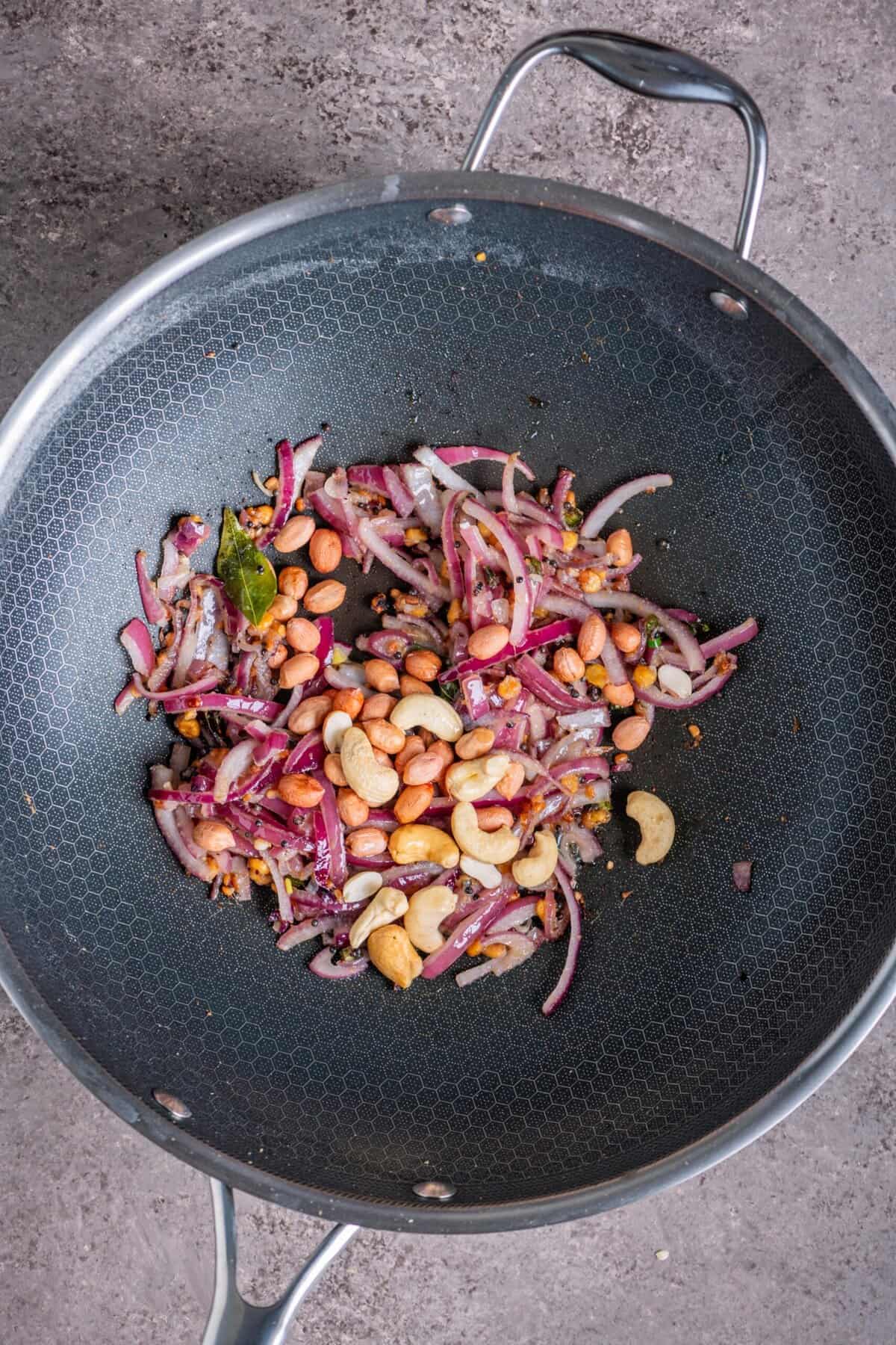 Cashews and peanuts roasting in pan for South Indian tomato upma.