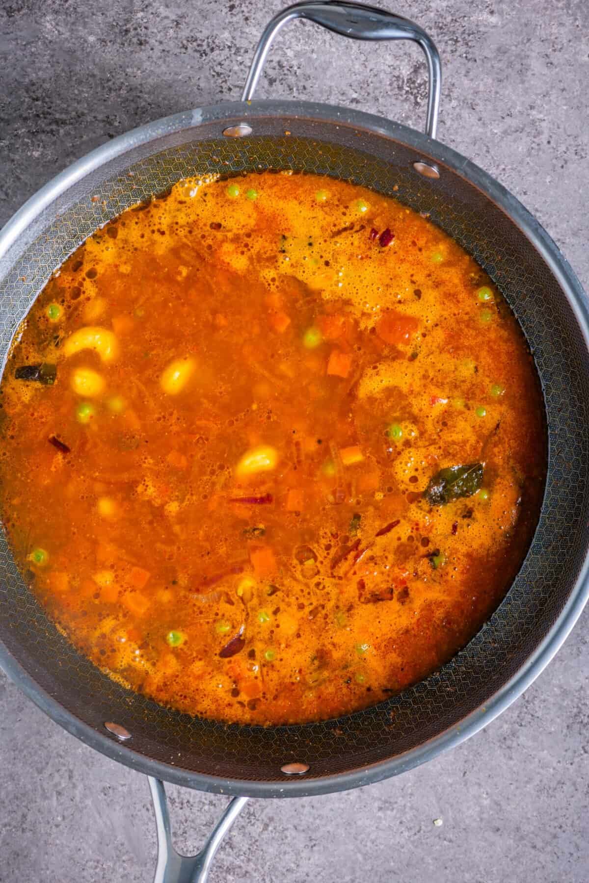 Water being added to tomato masala mixture for vegetable upma.