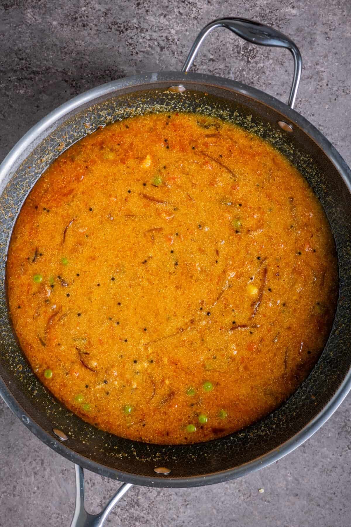 Cooking tomato rava upma in a pan.