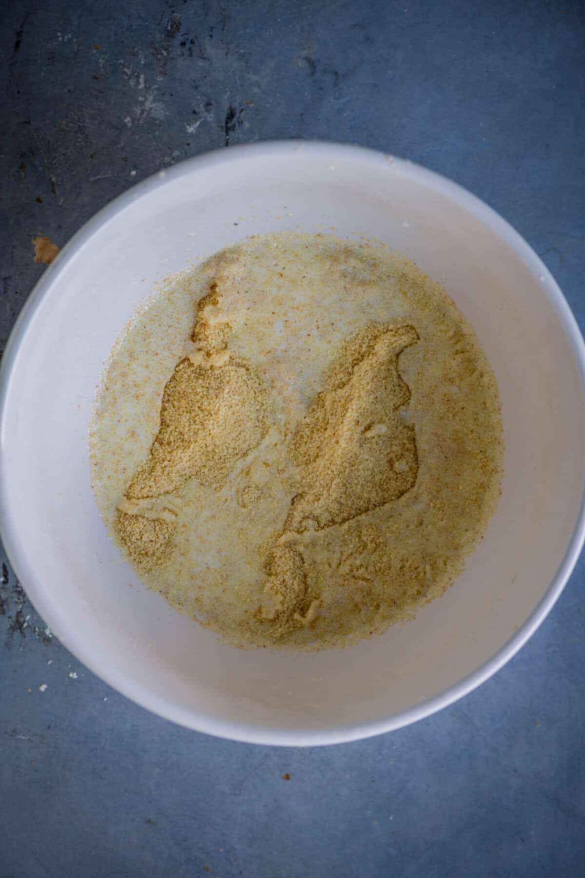 Pouring milk into rava for eggless gulab jamun cupcake batter.