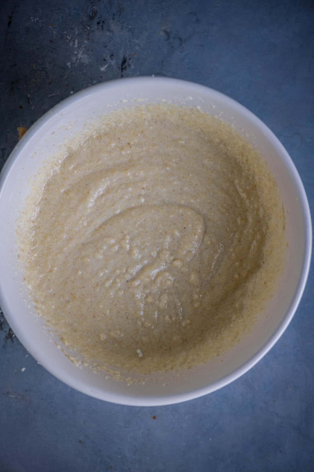 Whisked rava cake batter resting in a bowl before baking.