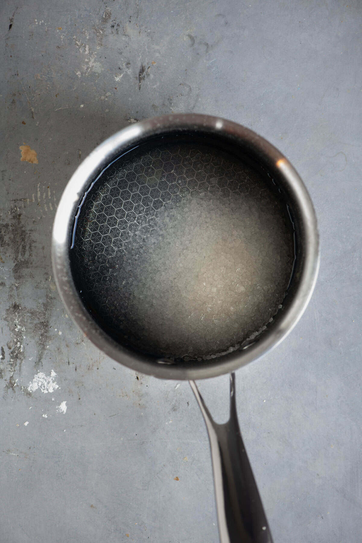 Sugar, and water added to a saucepan for gulab jamun sugar syrup.
