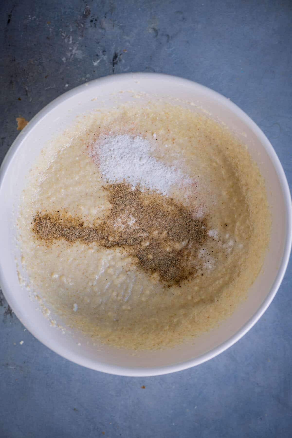 Adding cardamom powder, baking powder, baking soda, and salt to rested rava batter.