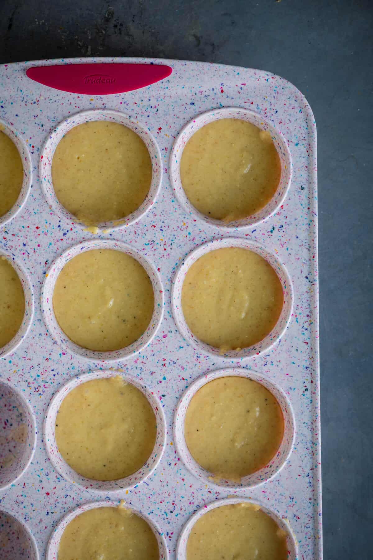 Gulab jamun cupcake batter filled into muffin molds ready to bake.