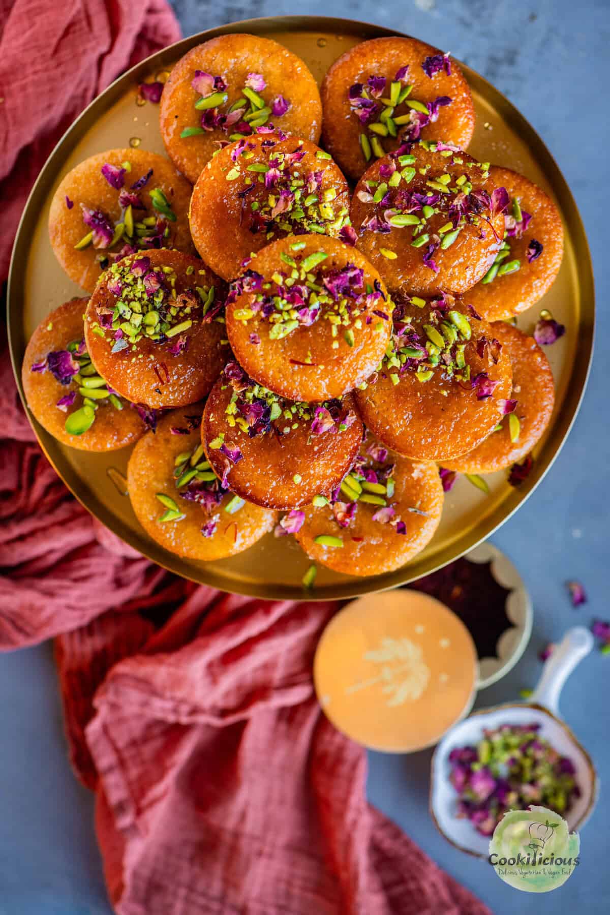 Gulab Jamun Cupcakes topped with pistachios and rose petals served in a plate.
