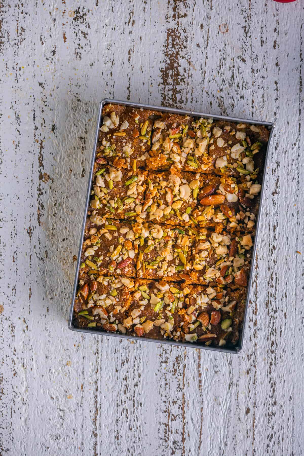Caramel coconut barfi cut into squares and cooling in the tray.