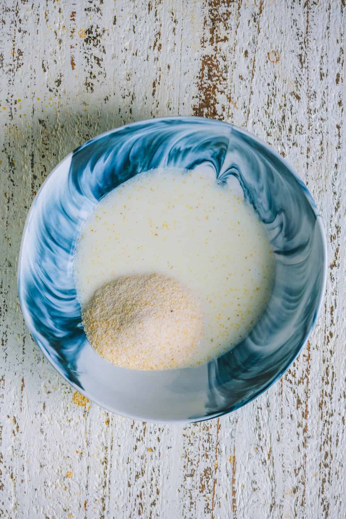 Milk and rava soaking together in a bowl for coconut barfi.