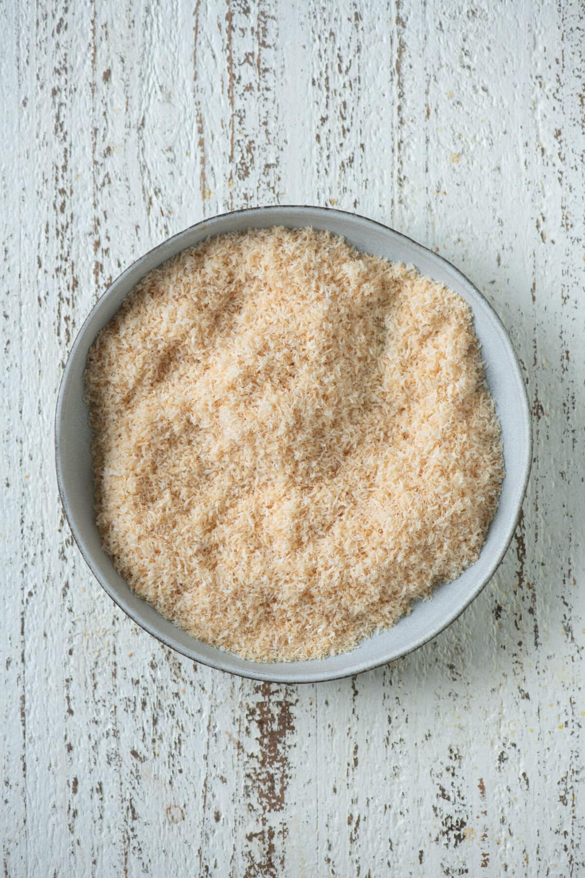 Golden roasted desiccated coconut transferred to a plate for coconut barfi.