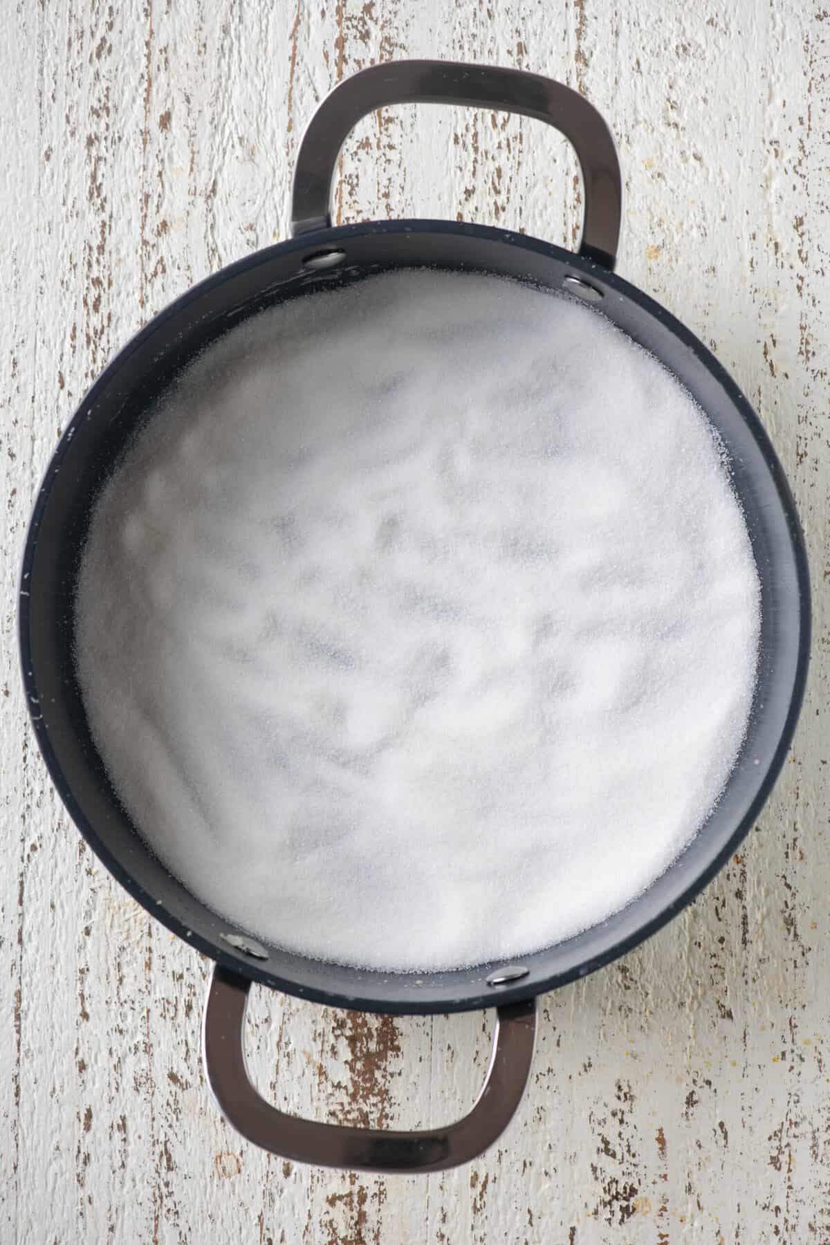 Sugar melting slowly in a pan to make caramel for coconut barfi.