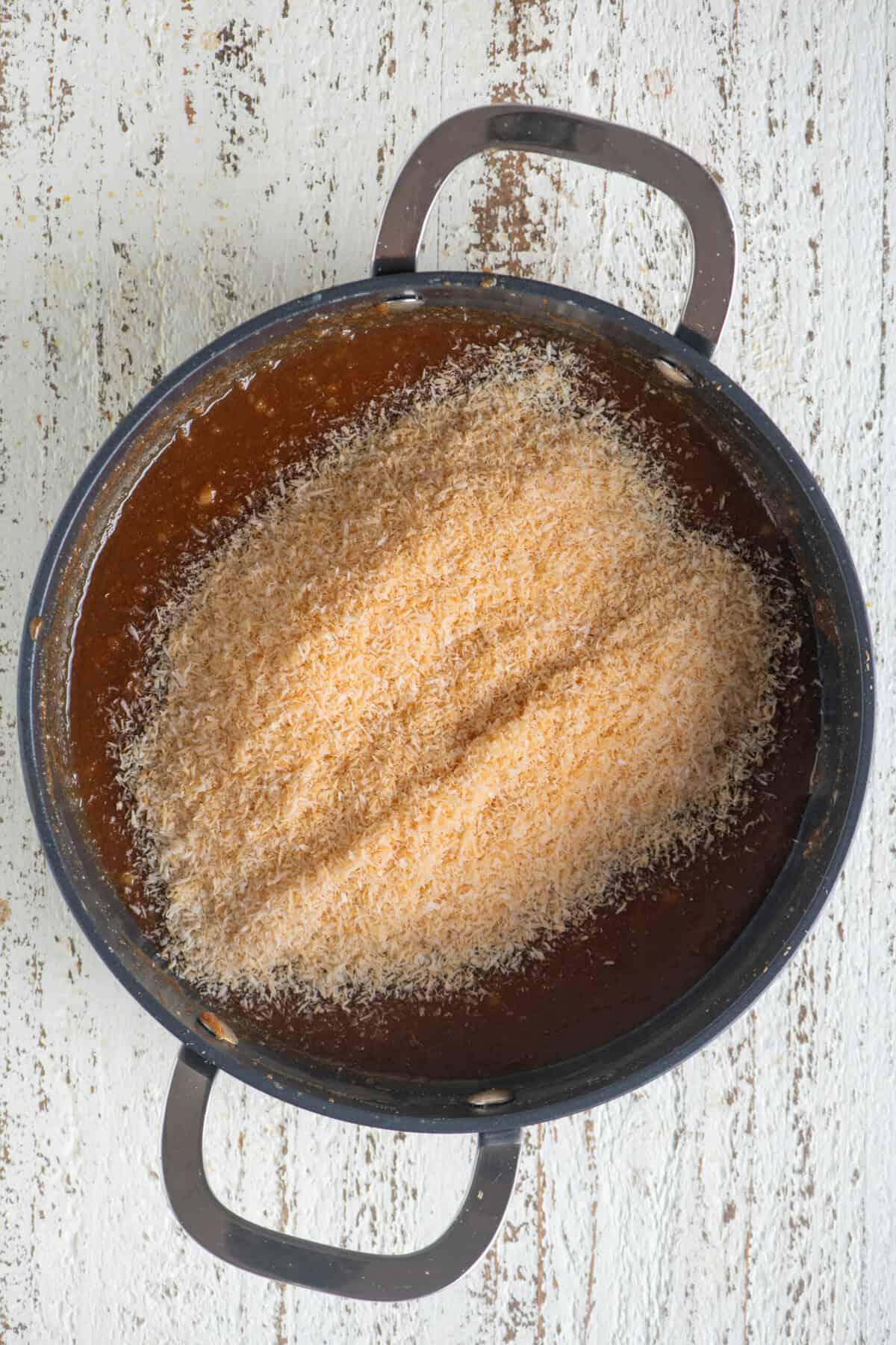 Roasted desiccated coconut added to the caramel-rava mixture.