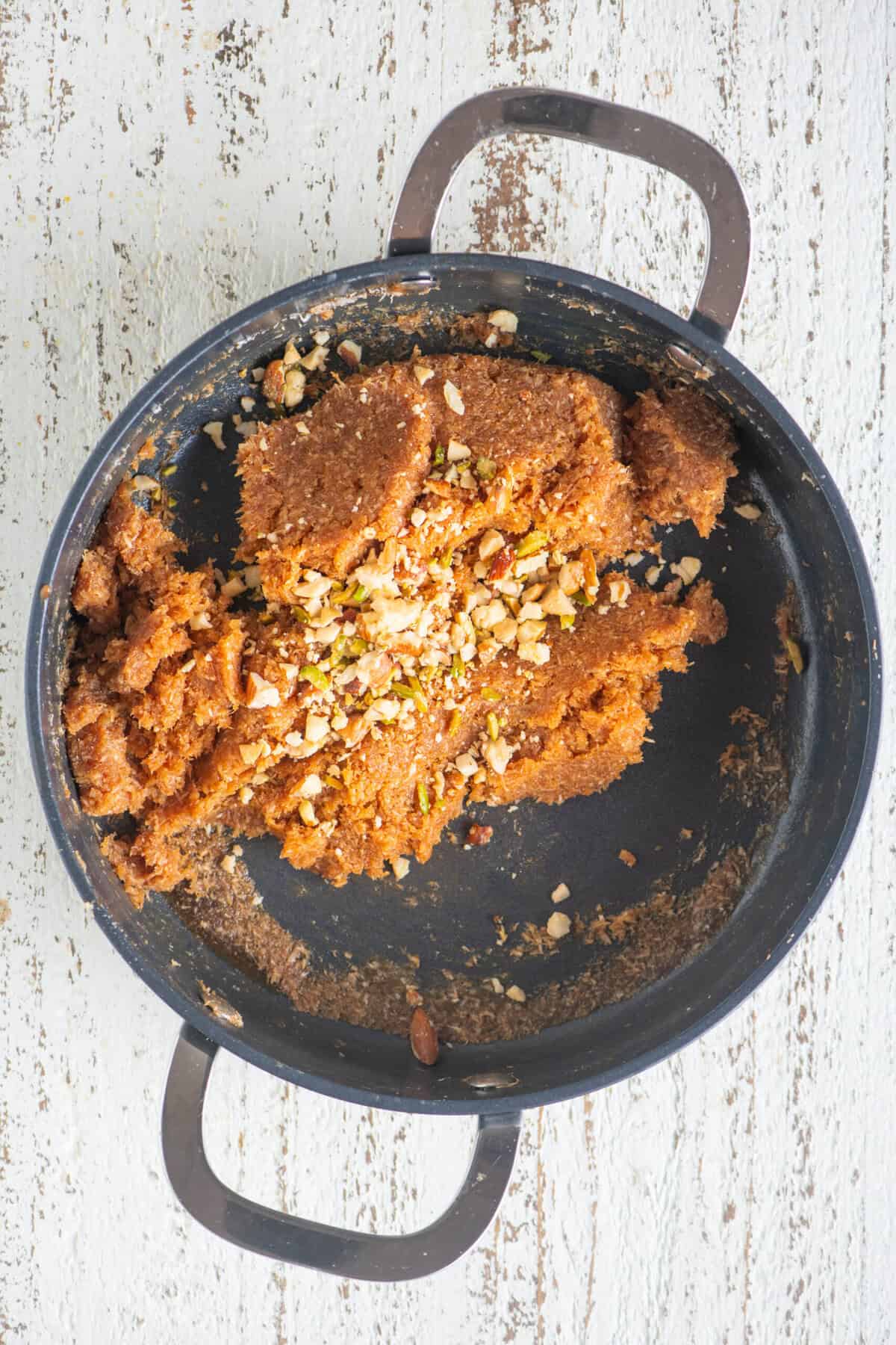 Cardamom powder and crushed nuts added to the nariyal barfi mixture.