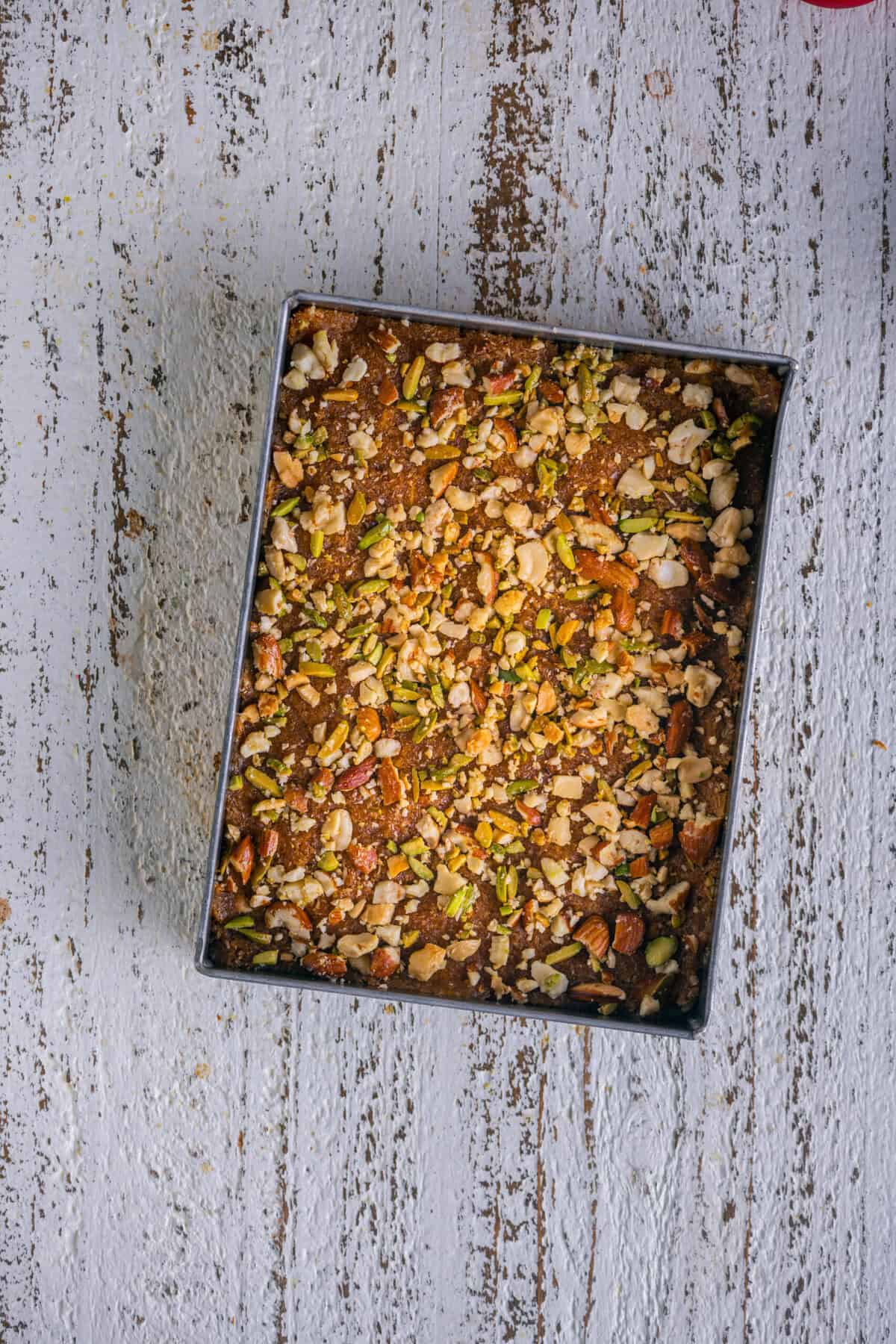 Crushed nuts sprinkled and pressed onto the caramel coconut barfi.
